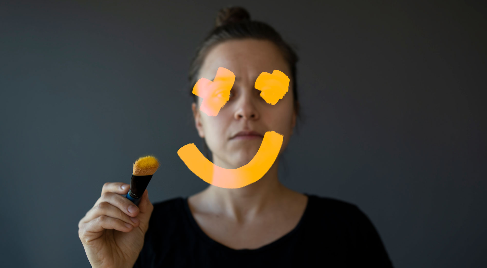 woman drawing smiley face on top of sad face